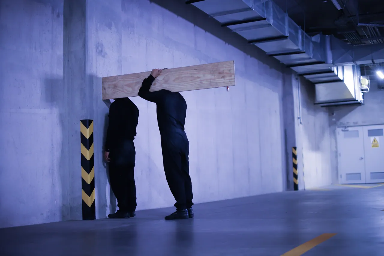 Two figures against a parking-garage wall, Los Innato series