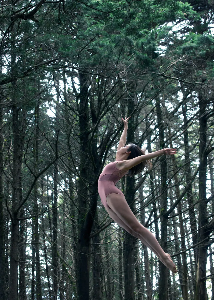 Bailarina saltando entre pinos